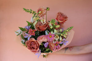 Locally made bouquet featuring roses, dahlias, cosmos, veronicas, foxglove, and clematis against a pink background, arranged by Solabee Flowers in Portland Oregon